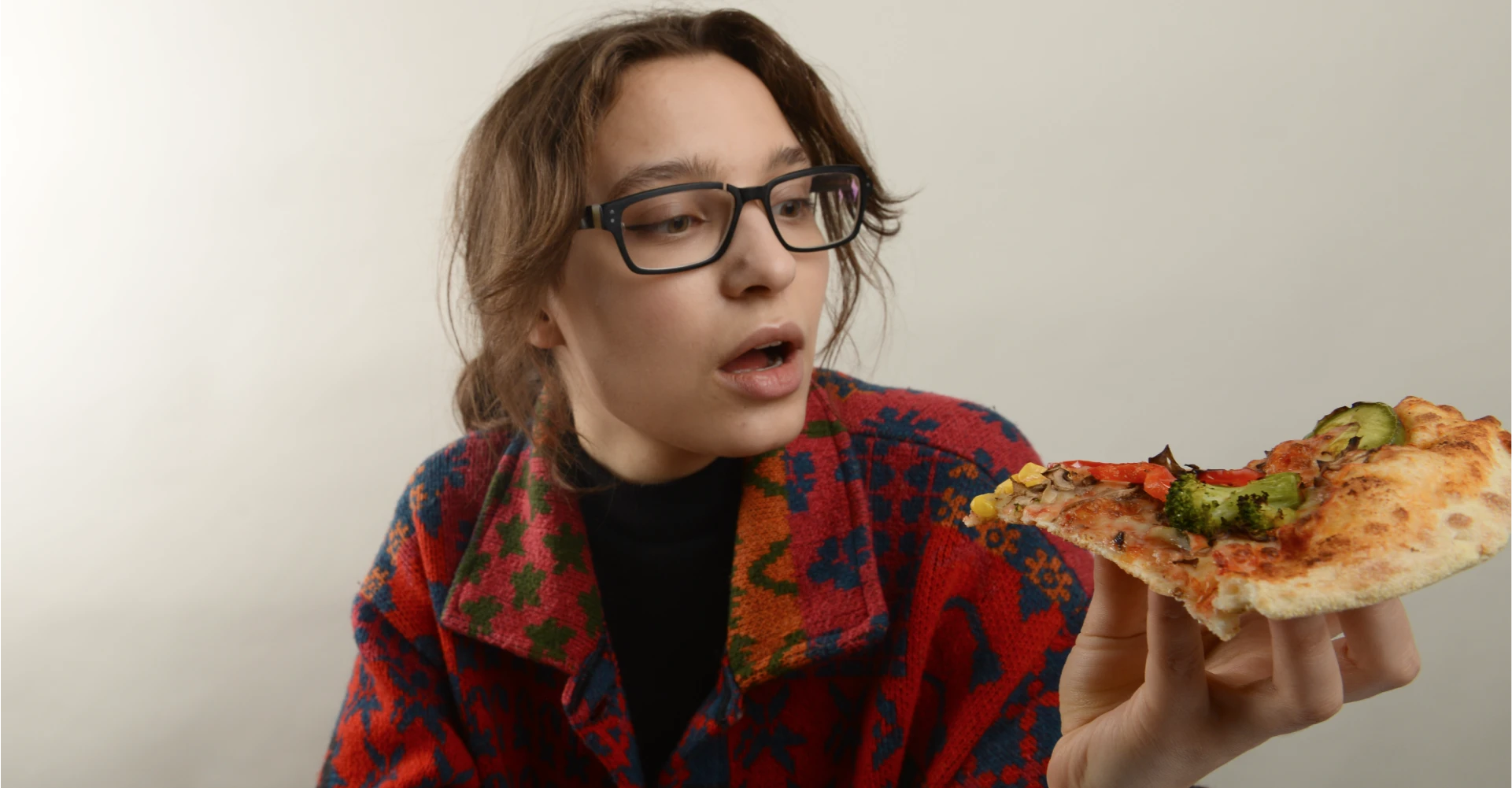 Kobieta z otwartymi ustami mająca zaraz ugryźć kawałek pizzy
